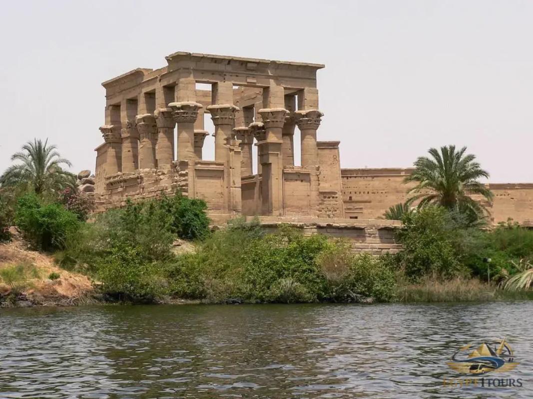 Scenic Nile River view sailing past the illuminated Philae Temple in Aswan