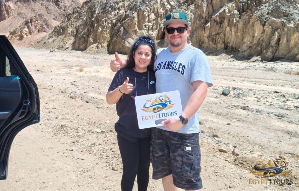 happy tourists holding egypt 1 tours banner during private transfer between luxor and aswan